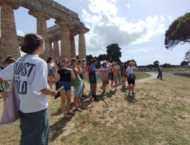 People gathered outside a massive building, chatting and taking photos.