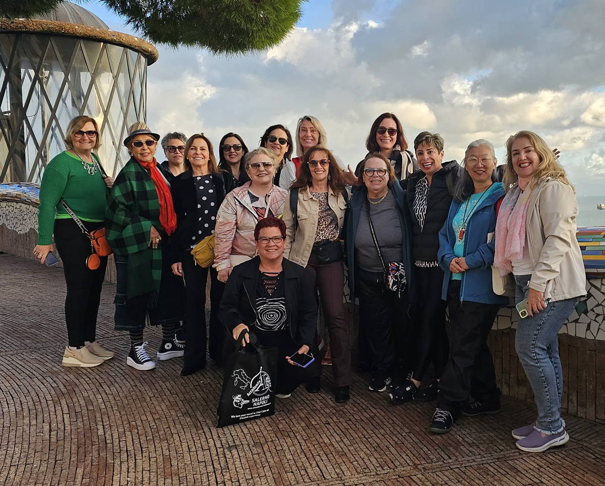 A group of women smiling and posing for a photo in front of a large building, showcasing camaraderie and joy.