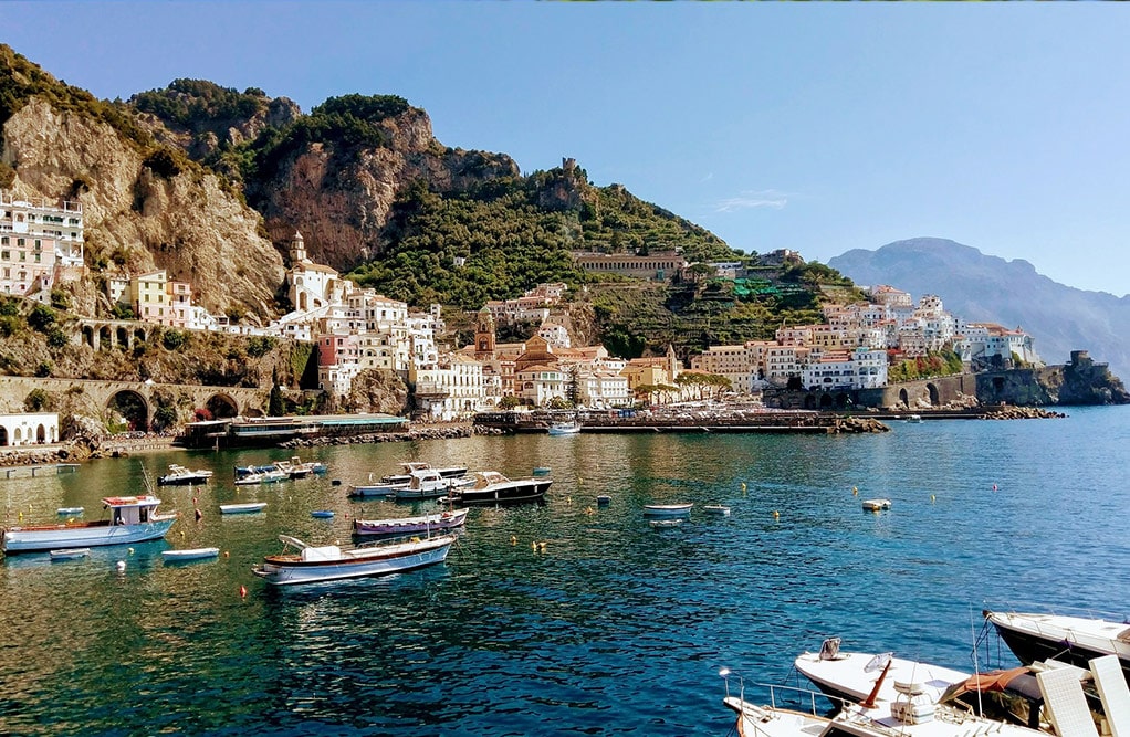 Aerial view of Amalfi, Italy, showcasing its stunning coastline, colorful buildings, and lush mountainous backdrop.